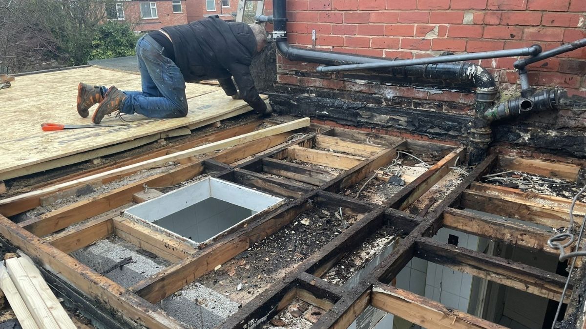 Dark grey resin driveway leading to a white garage door, flanked by gardens with greenery.