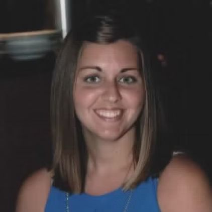 A woman in a blue tank top is smiling for the camera.