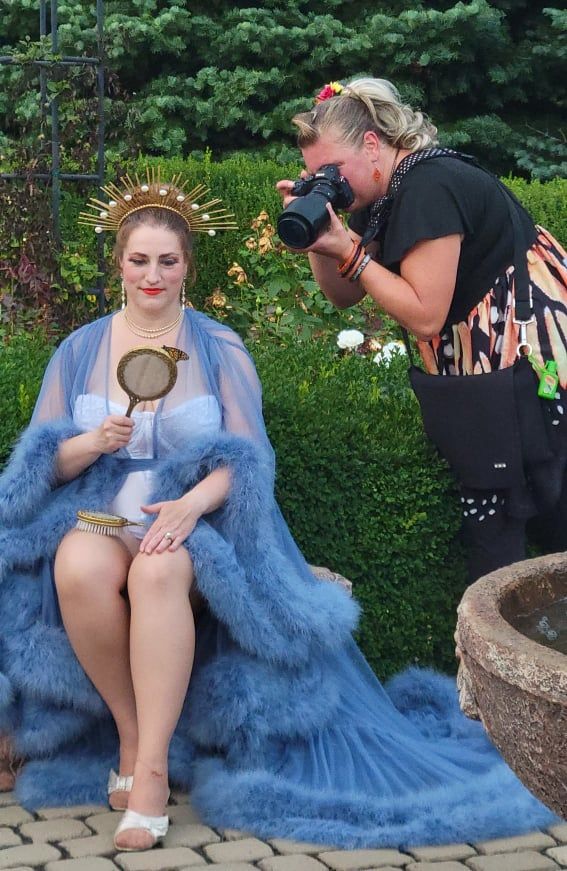 a woman is taking a picture of a woman in a blue dress holding a mirror .