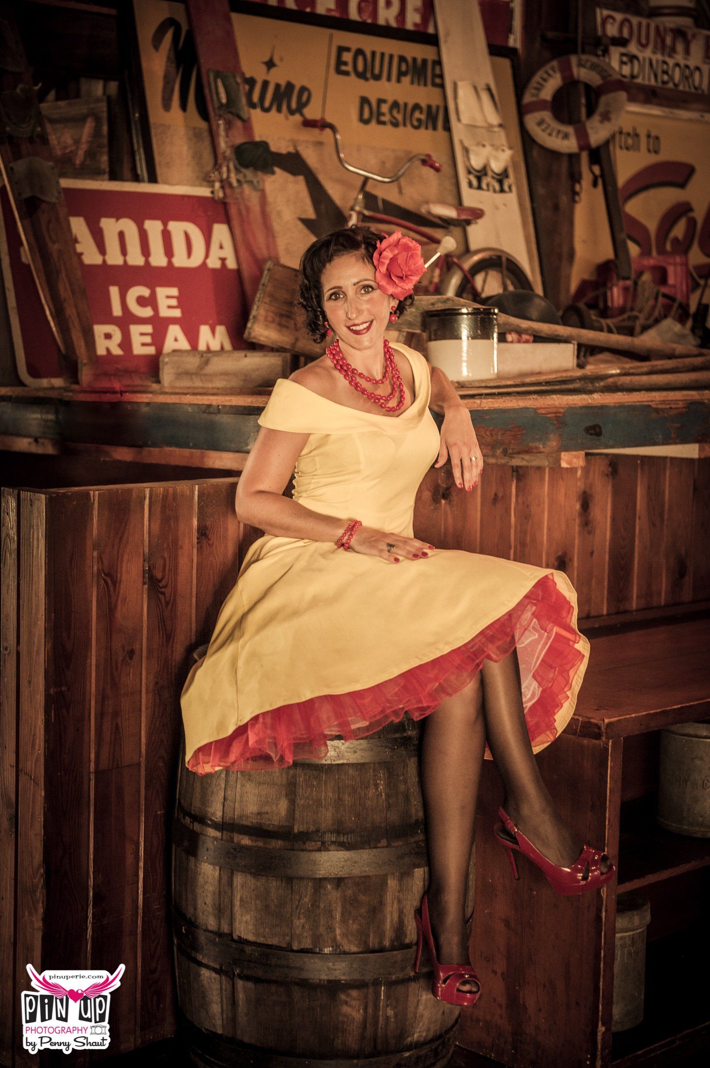a woman in a yellow dress is sitting on a wooden barrel .