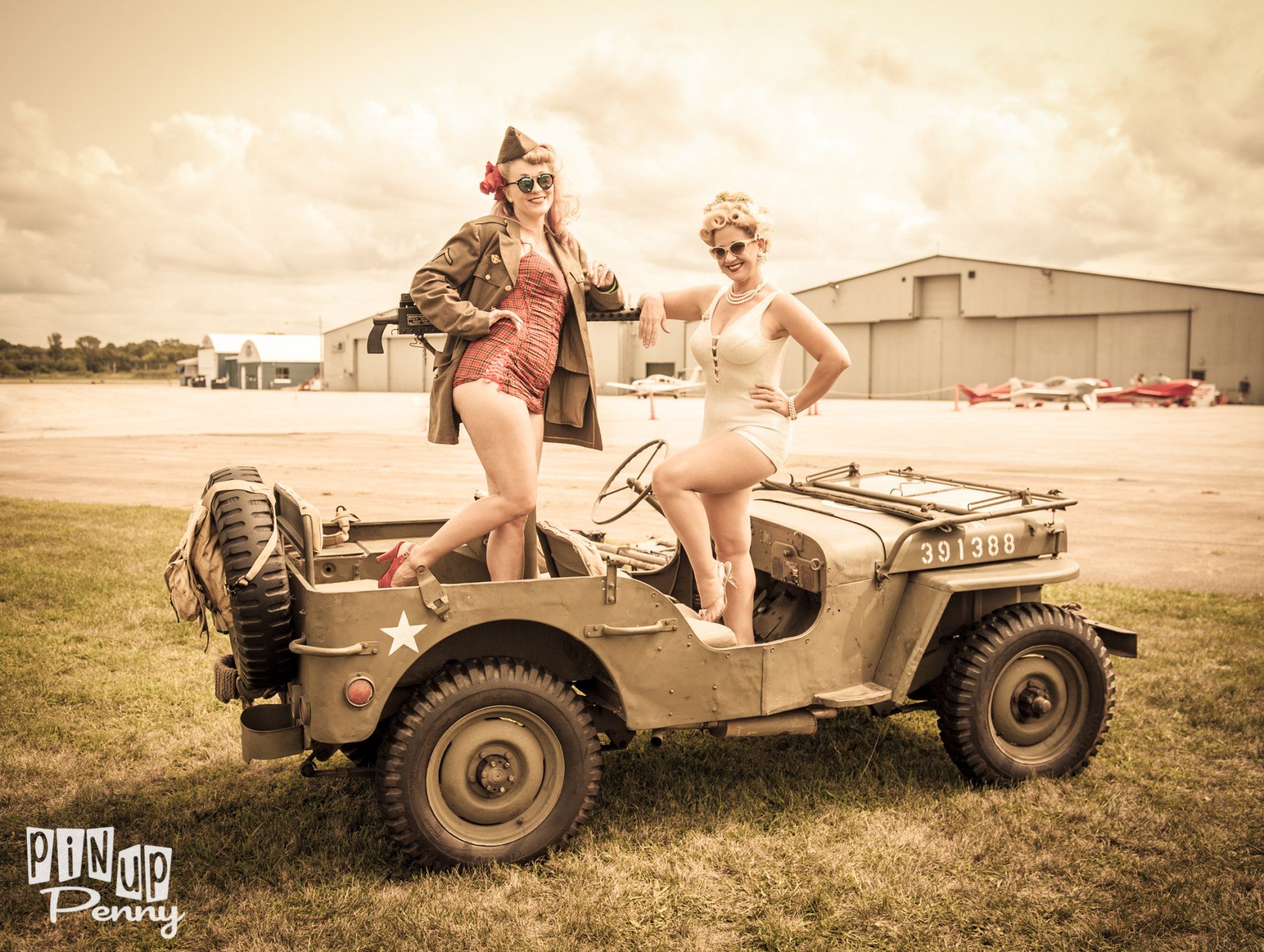 two women are standing next to a military jeep .