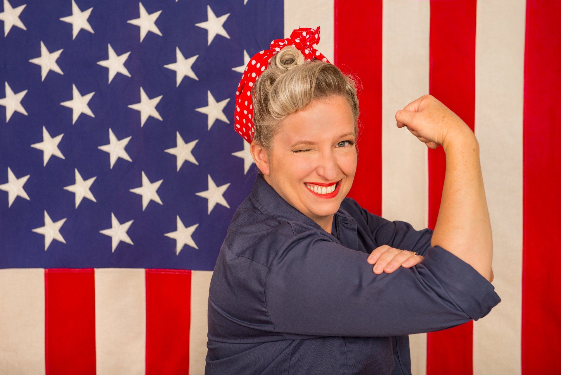 a woman is flexing her muscles in front of an american flag .