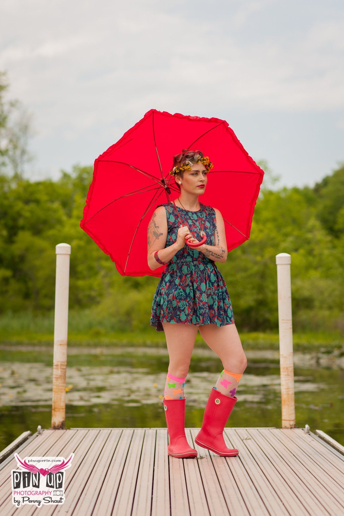 a woman is standing on a dock holding a red umbrella .