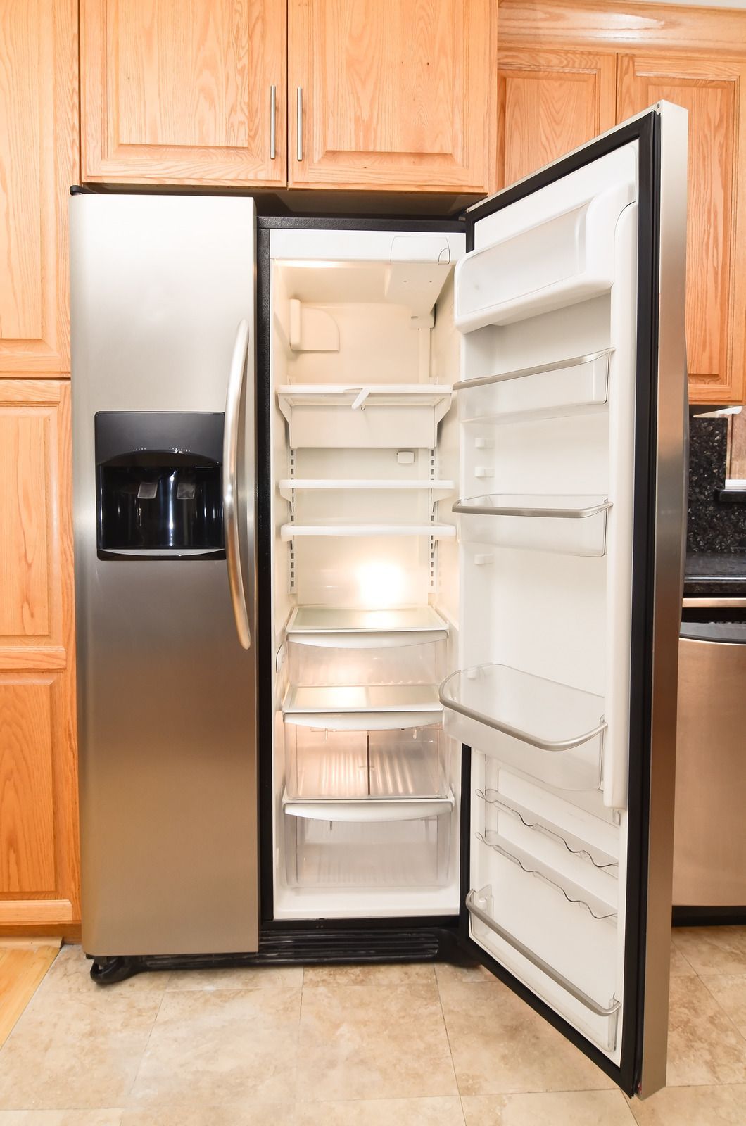 A man is fixing a refrigerator in a kitchen.