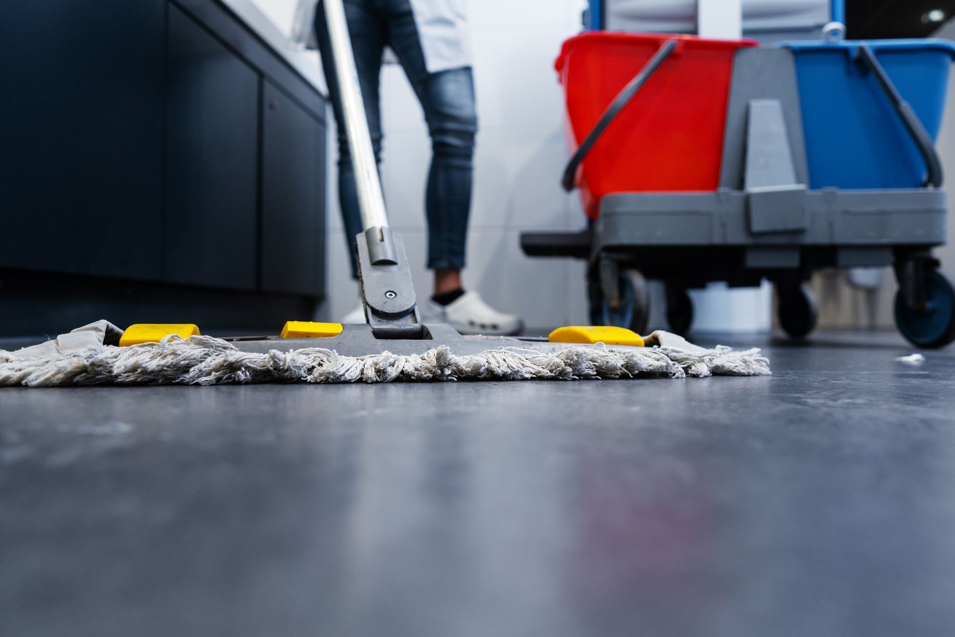 A woman is cleaning the floor with a mop and vacuum cleaner.