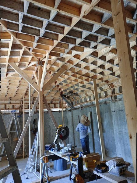 Construction of a wooden ceiling with a grid pattern. Workers use power tools inside a building.