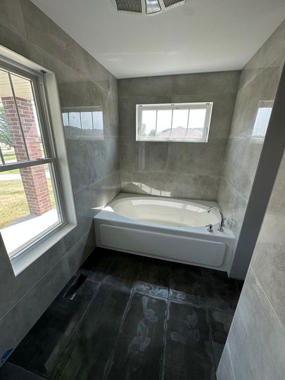 A bathroom with a bathtub and a window.