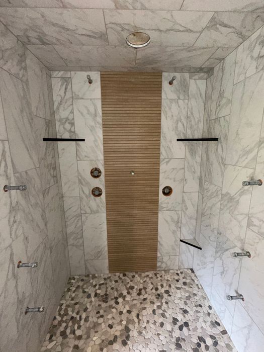 A shower with marble tiles and a wooden door