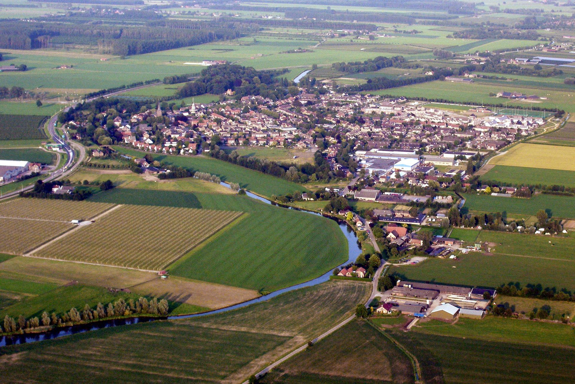Een luchtfoto van een klein stadje omgeven door velden