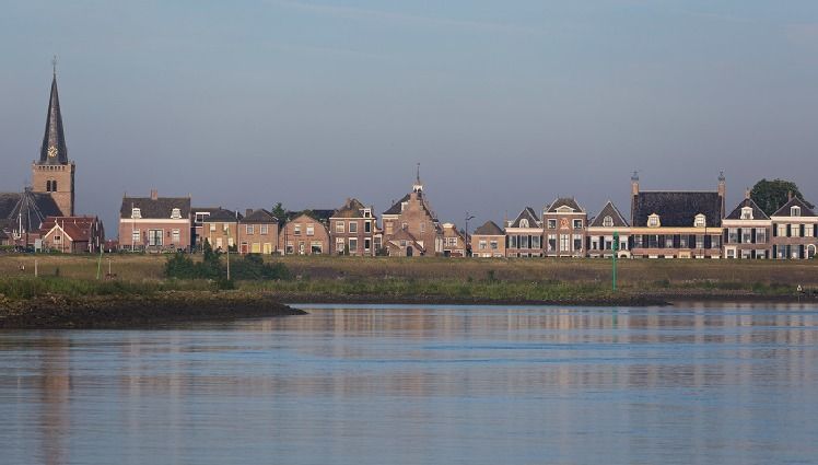 Een rij gebouwen langs een waterpartij met een kerk op de achtergrond.