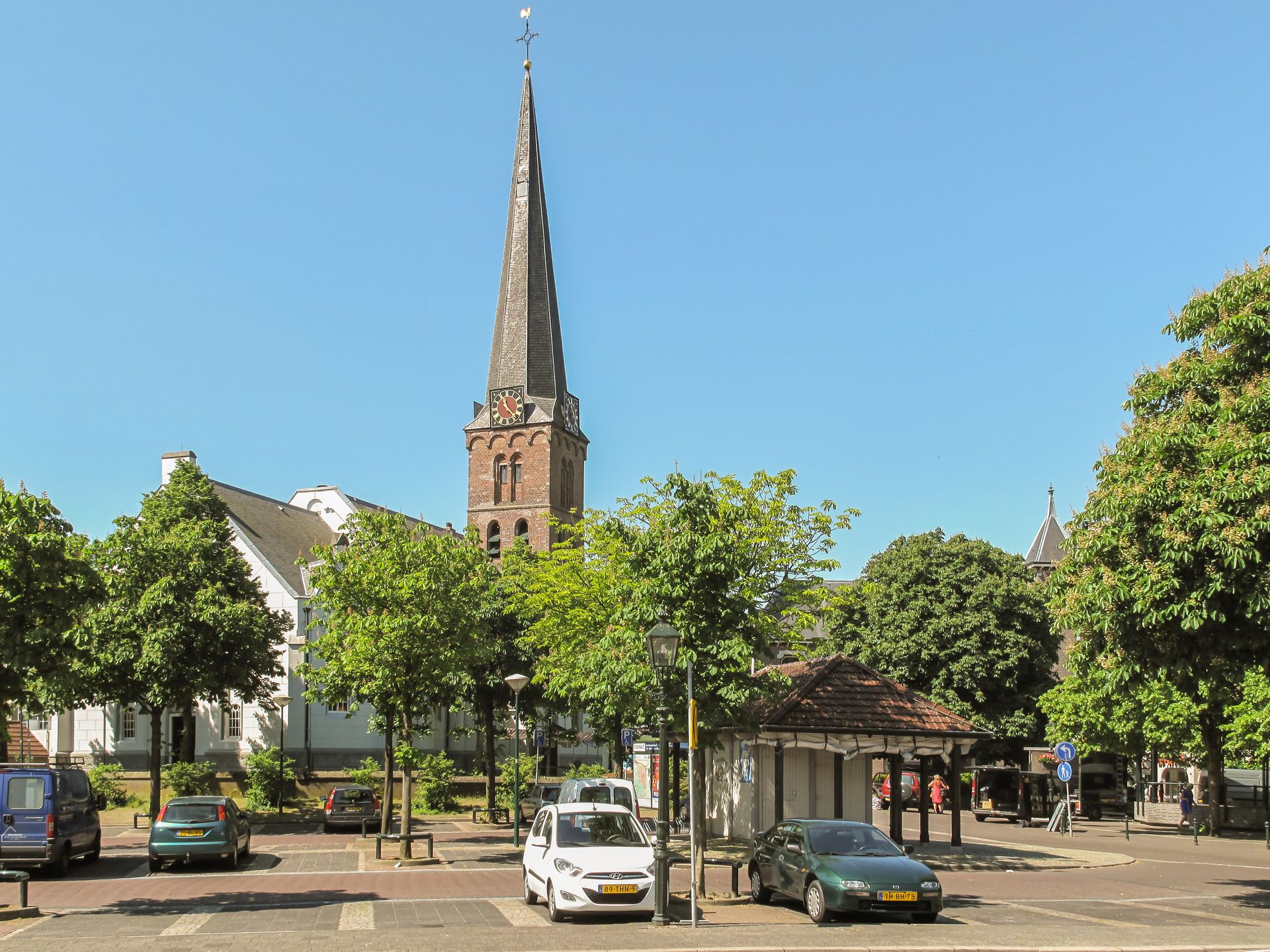 Auto's staan ​​geparkeerd voor een kerk met een torenspits