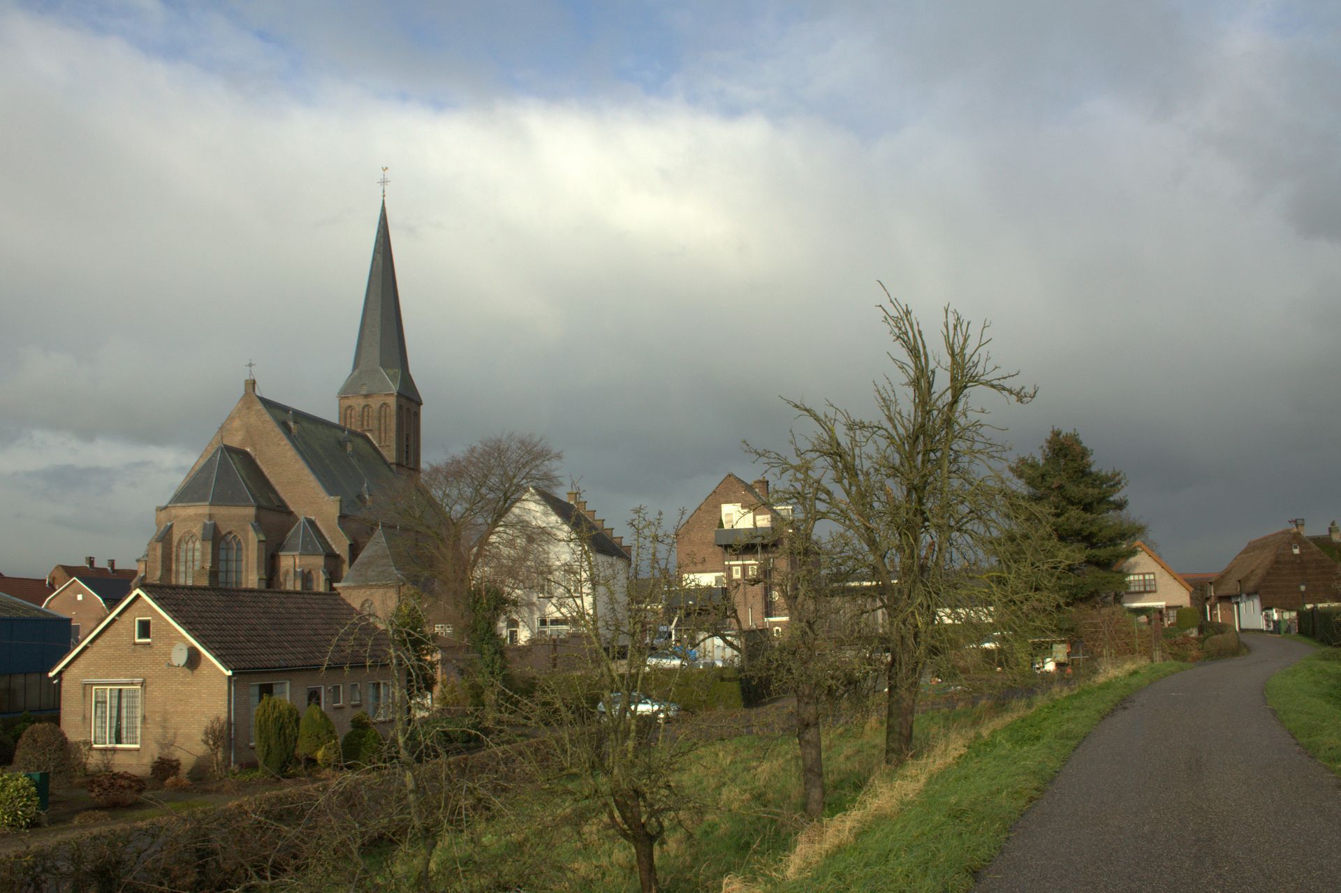 Een kerk met een torenspits is omringd door huizen op een bewolkte dag