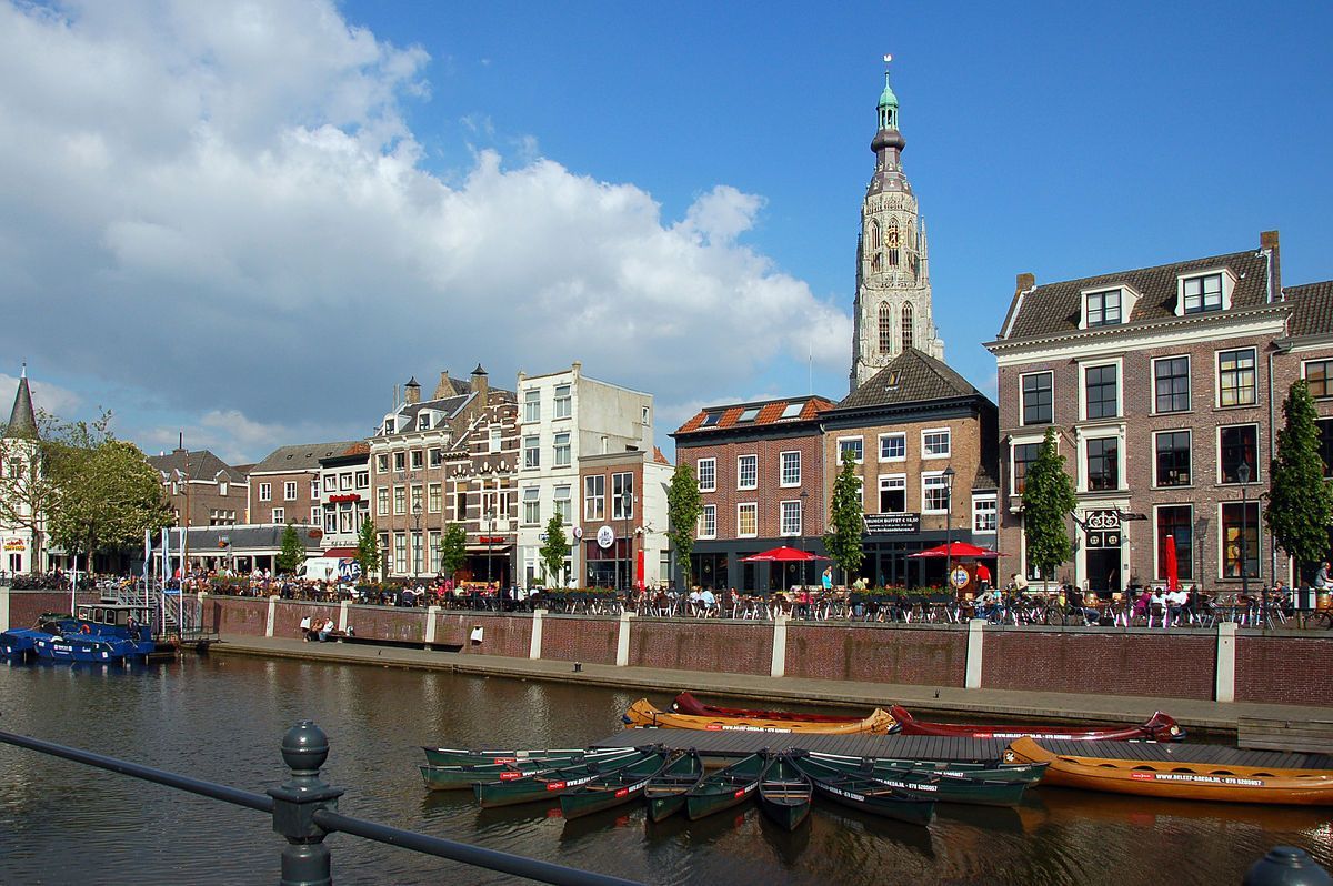 Een stad met boten op het water en een klokkentoren op de achtergrond