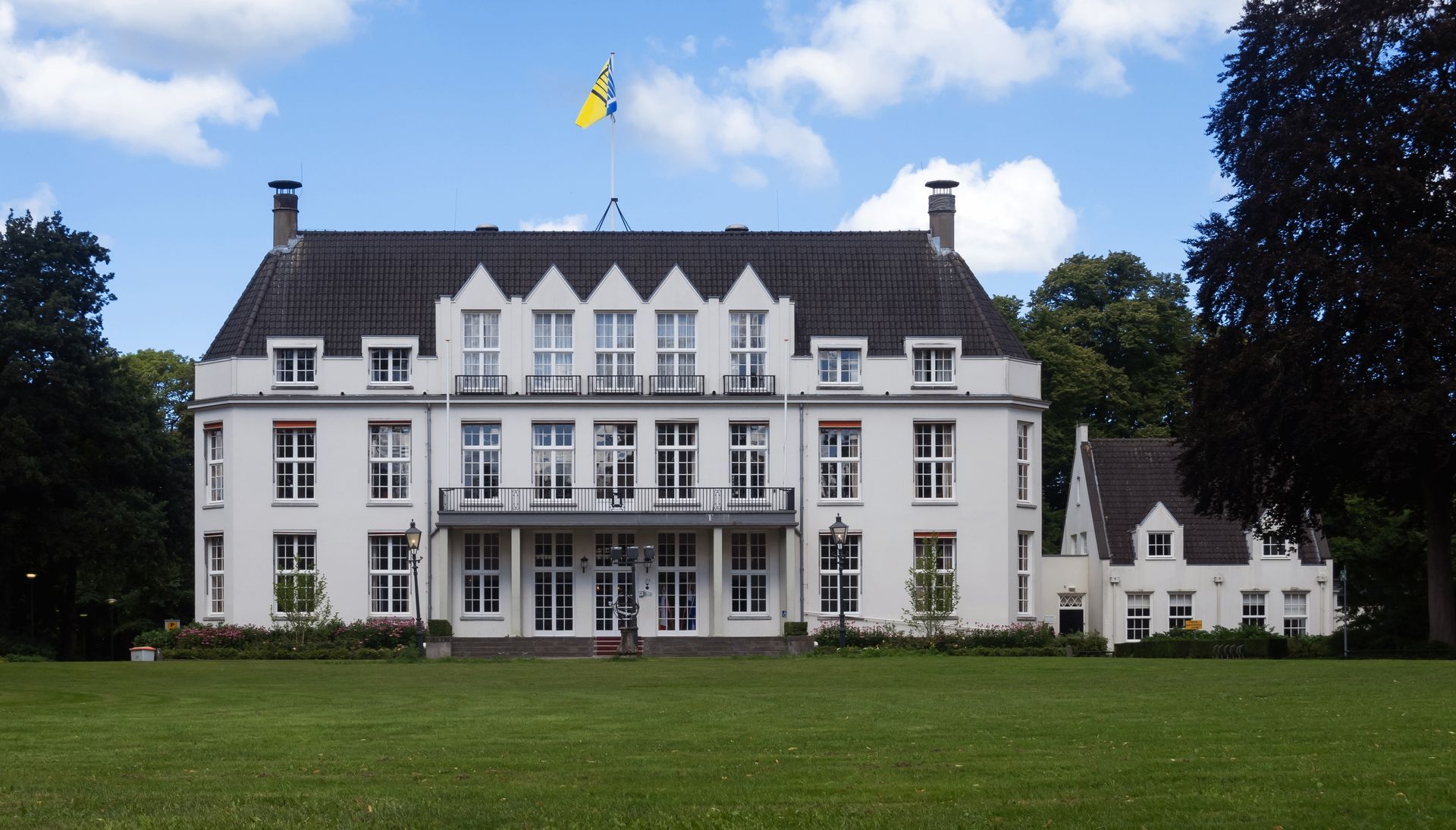 Een groot wit gebouw met een gele vlag erop