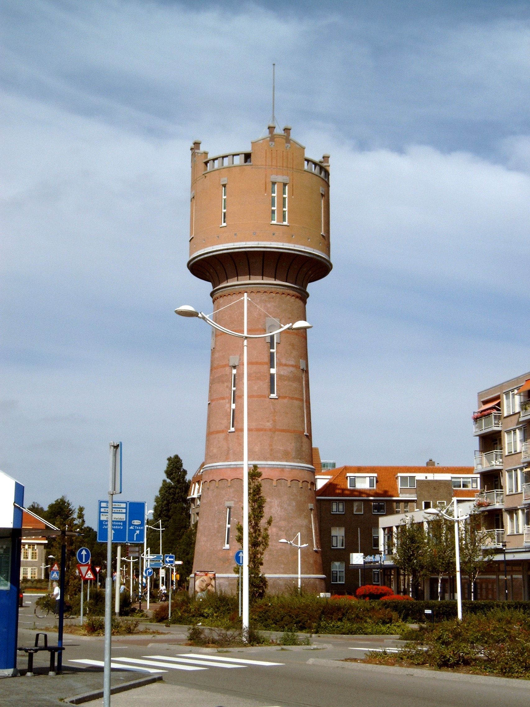 Een grote bakstenen watertoren staat midden in een stad