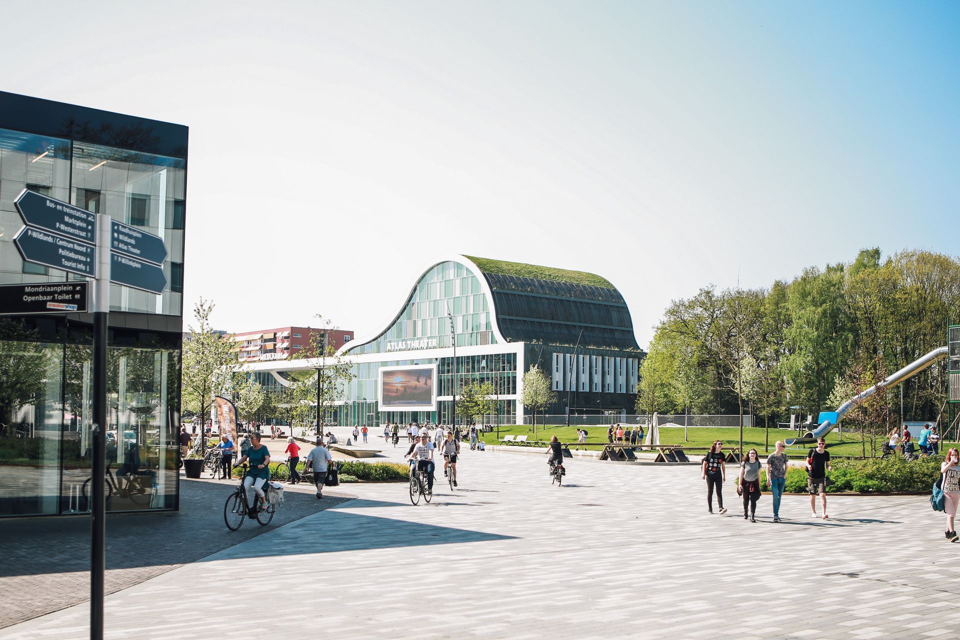 Een groep mensen loopt in een park voor een gebouw.