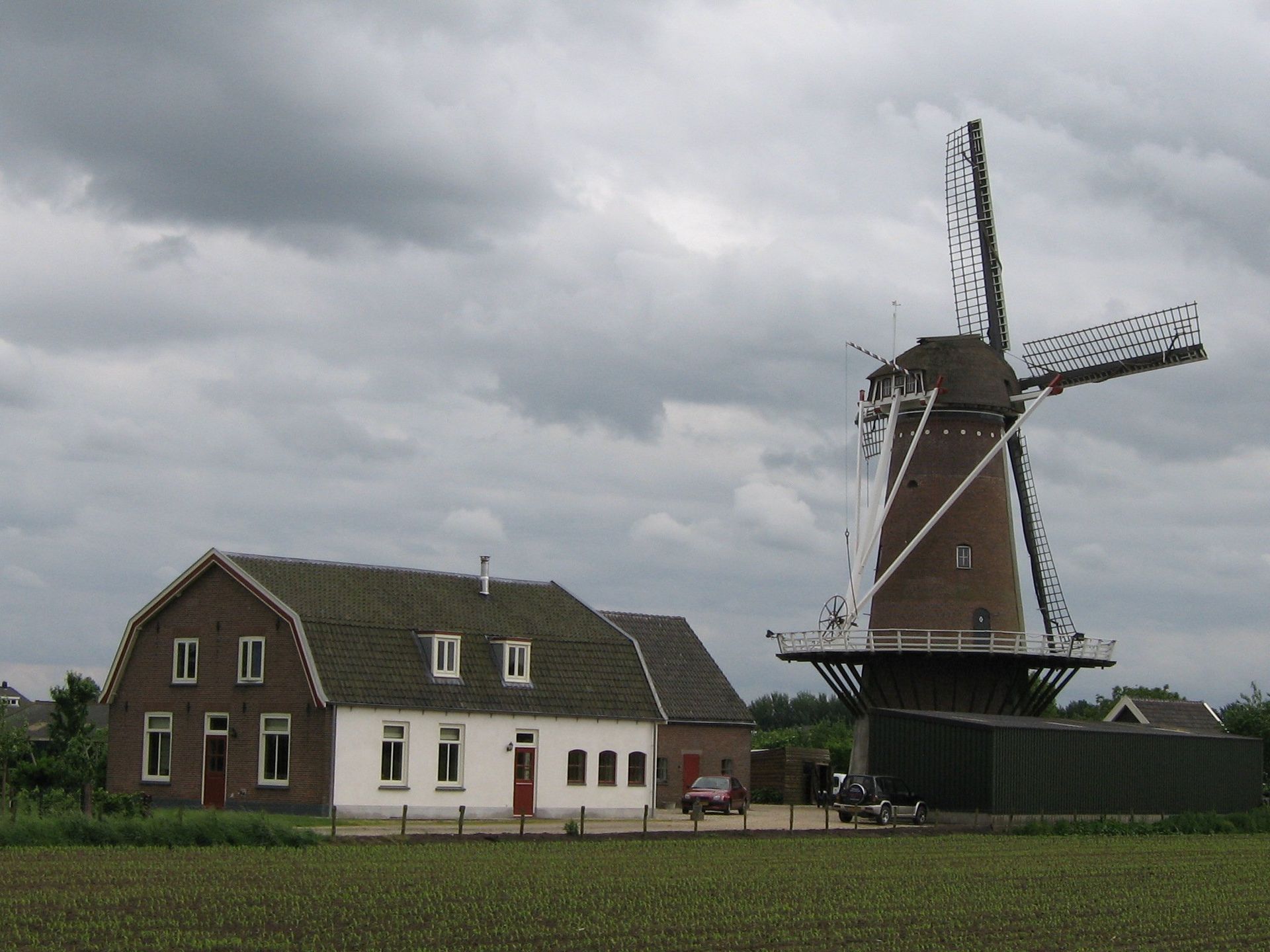 Een huis en een windmolen in een veld op een bewolkte dag