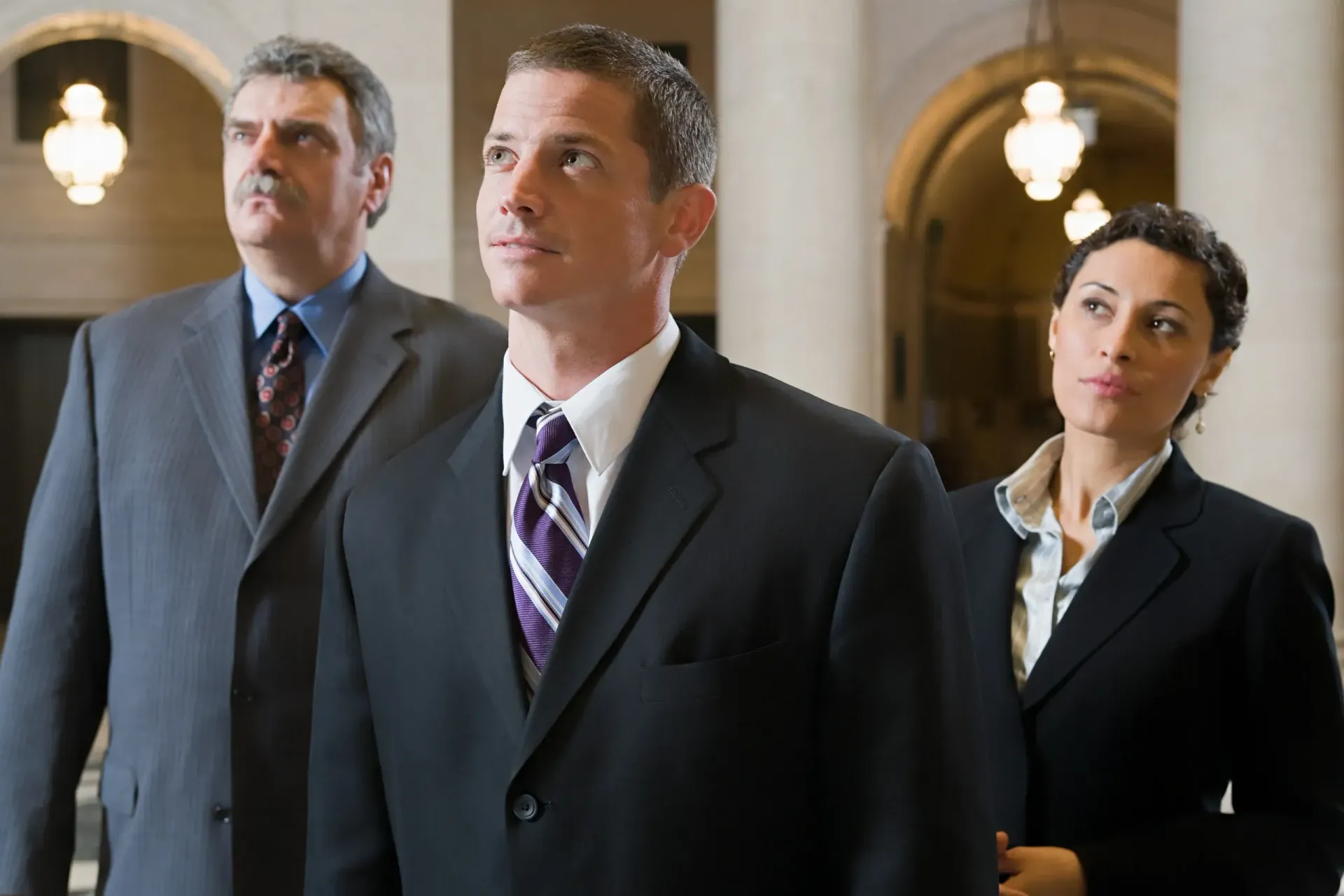 A woman in an apron and yellow gloves is holding a plate and a sponge.