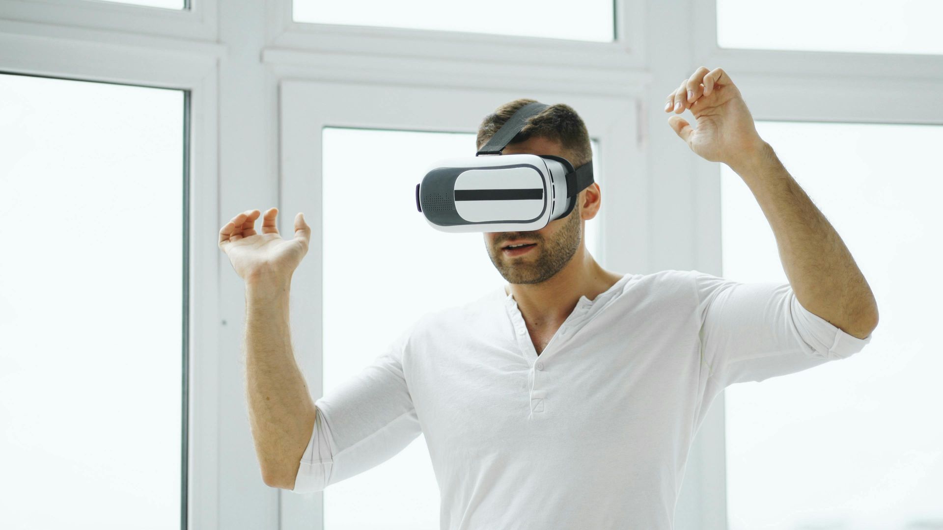 Une personne portant un casque de réalité virtuelle dans une pièce lumineuse lève les deux poings en signe d'excitation.