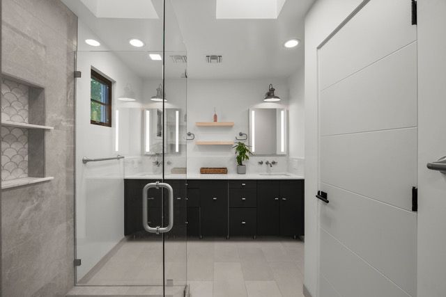 Modern bathroom with glass shower, black vanity, and white walls.