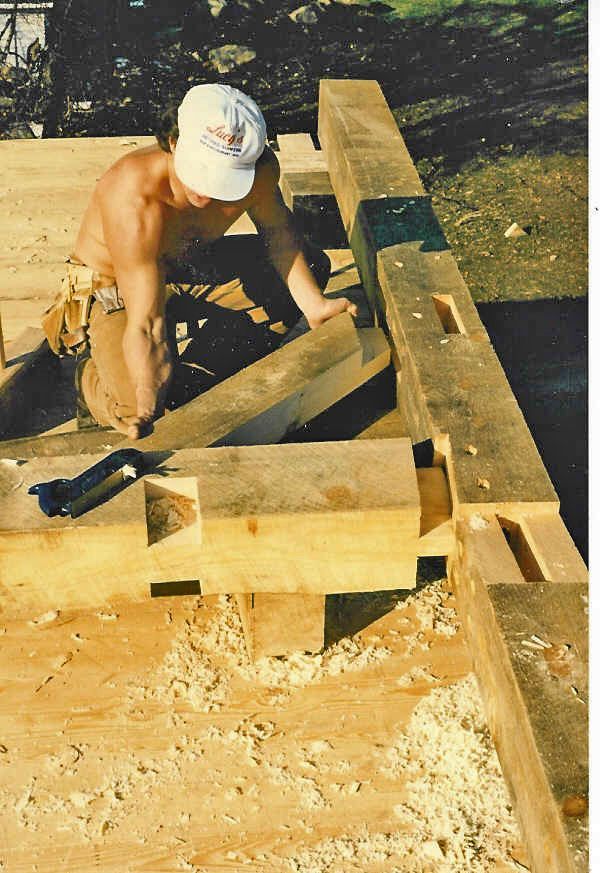 A shirtless man is working on a wooden structure