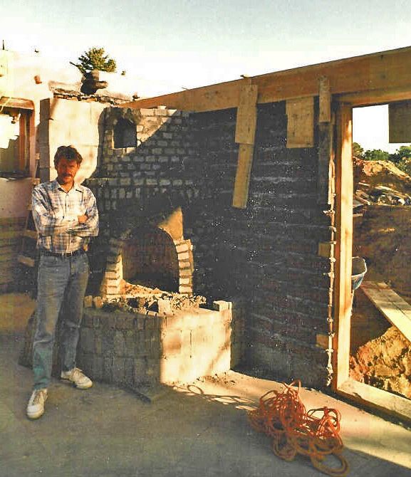 A man standing in front of a brick wall with his arms crossed