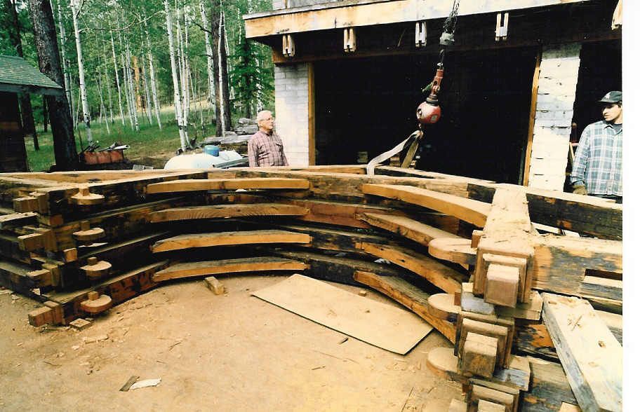 A man is standing in front of a stack of wood