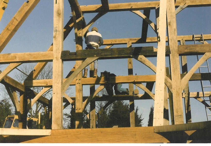 A man in a blue and white shirt is working on a wooden structure