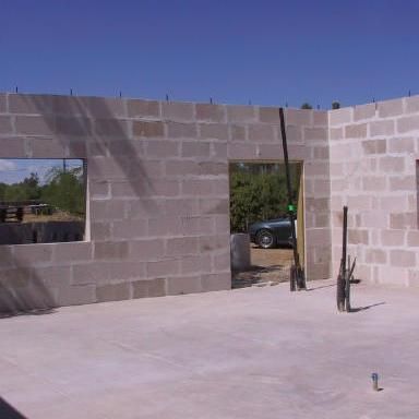 A brick building under construction with a car parked in the background.