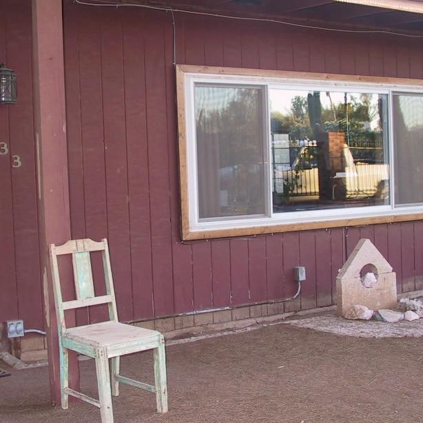 A chair is sitting in front of a window on the side of a house.
