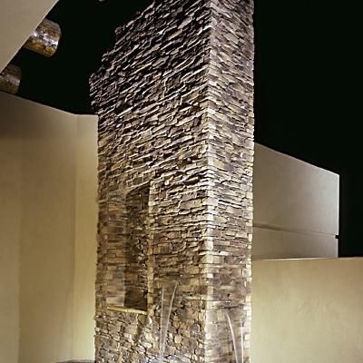 A large stone chimney in a room with a black ceiling