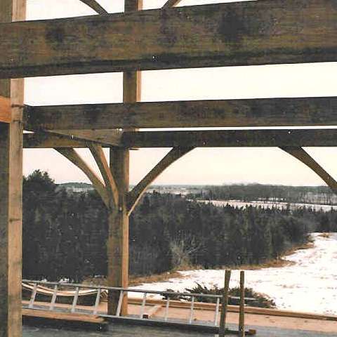 A wooden structure under construction with a view of a snowy forest.