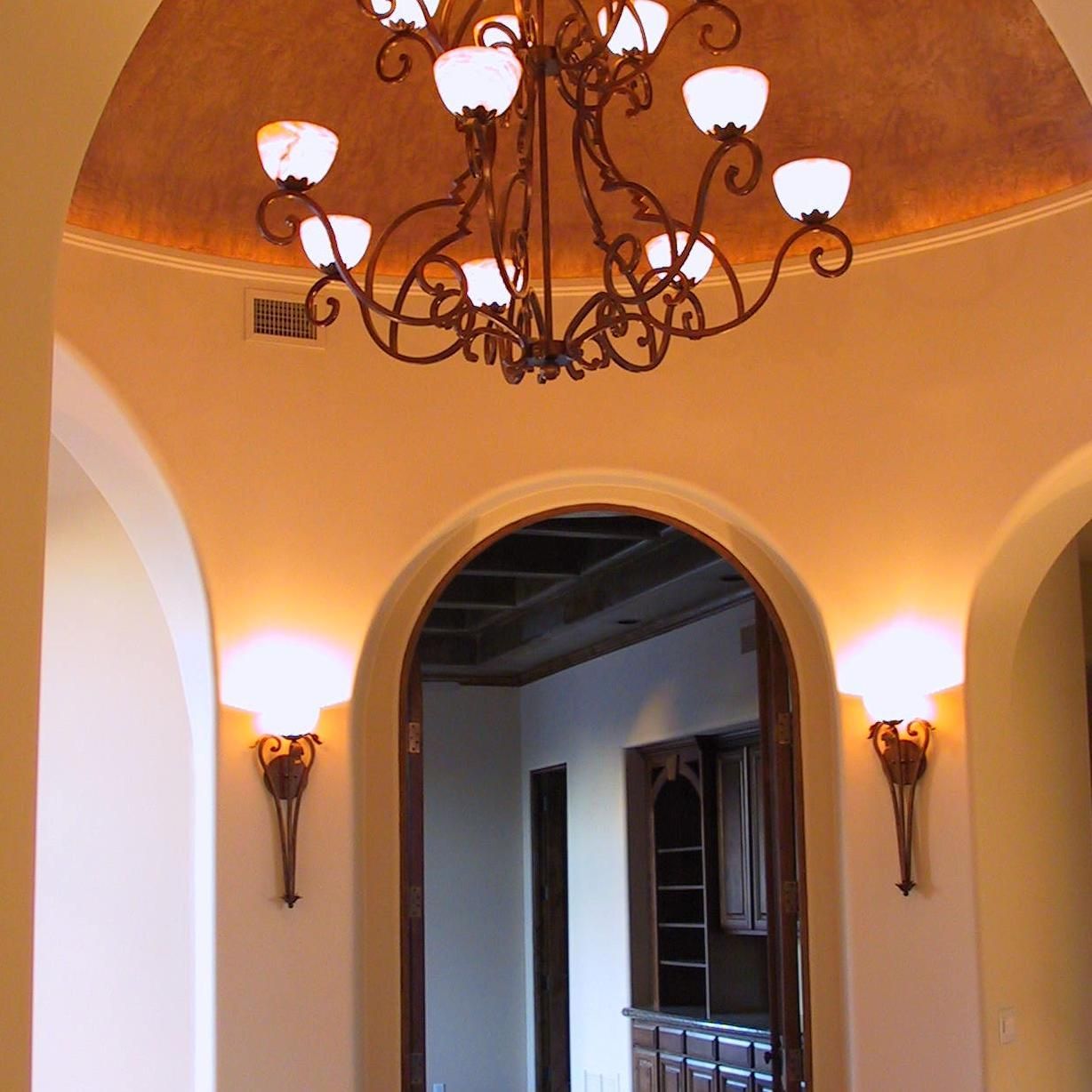 A hallway with arches and a chandelier hanging from the ceiling