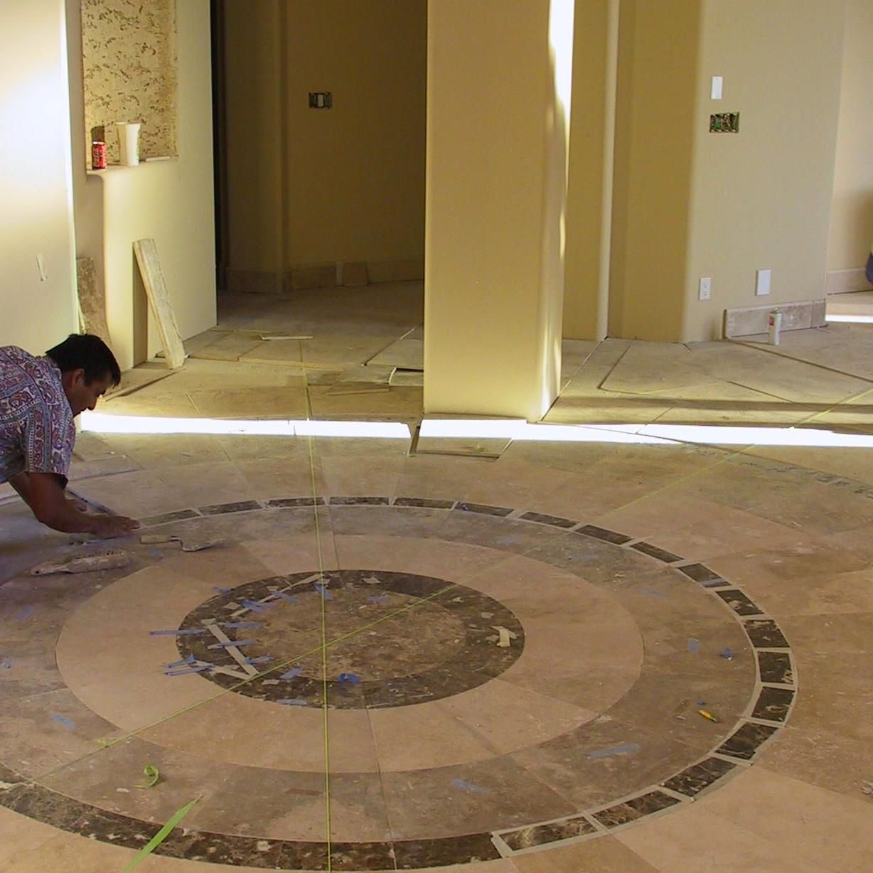 A man is measuring a circle on a tile floor
