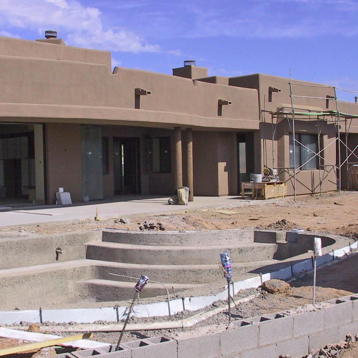 A house under construction with a pool in front of it
