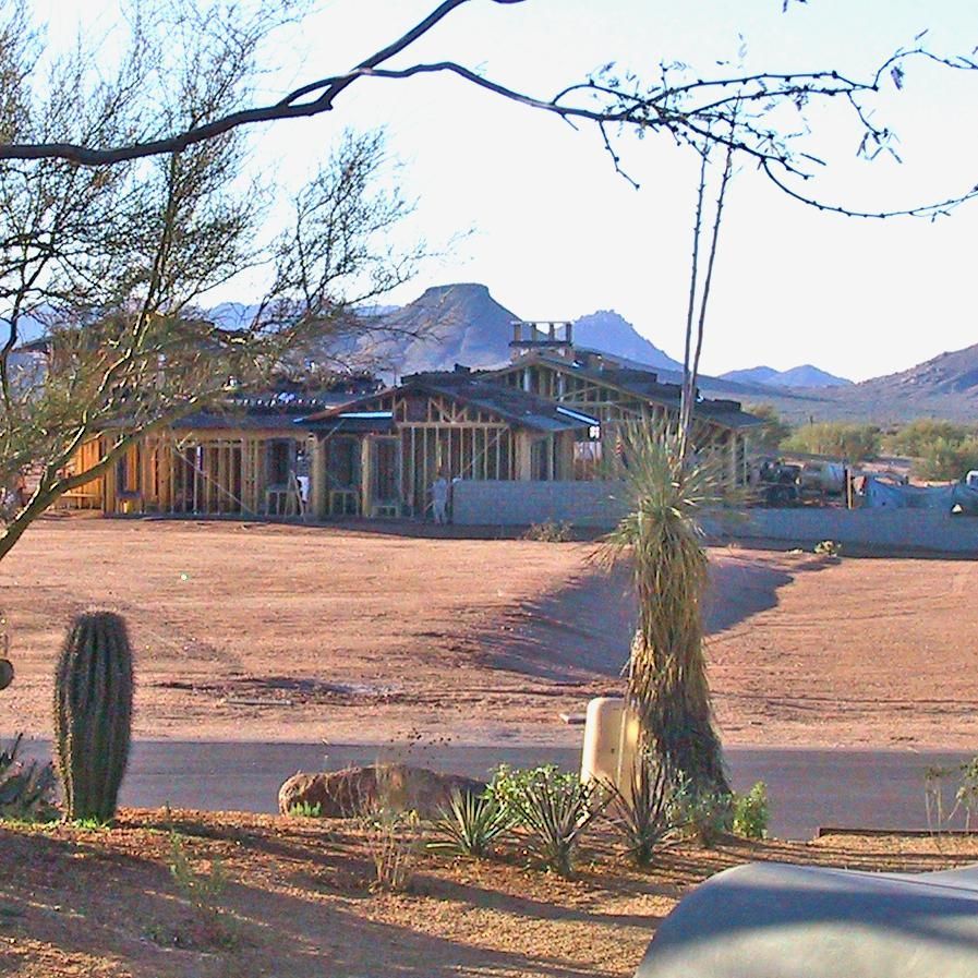A house is being built in the desert with mountains in the background