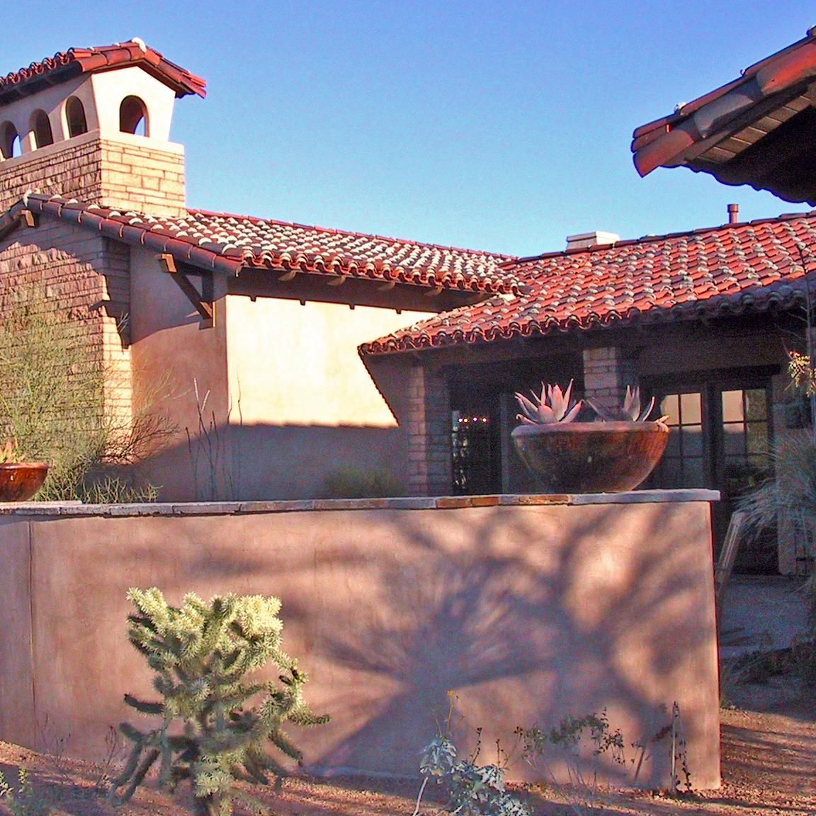 A house with a red tile roof and a cactus in front of it
