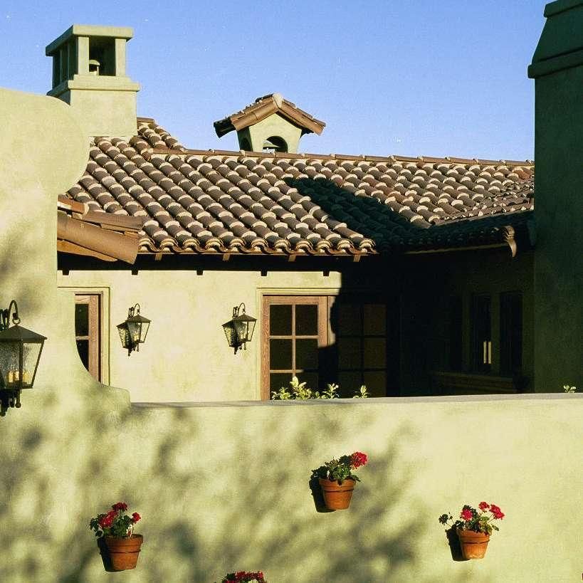 A house with a tiled roof has a chimney on top of it
