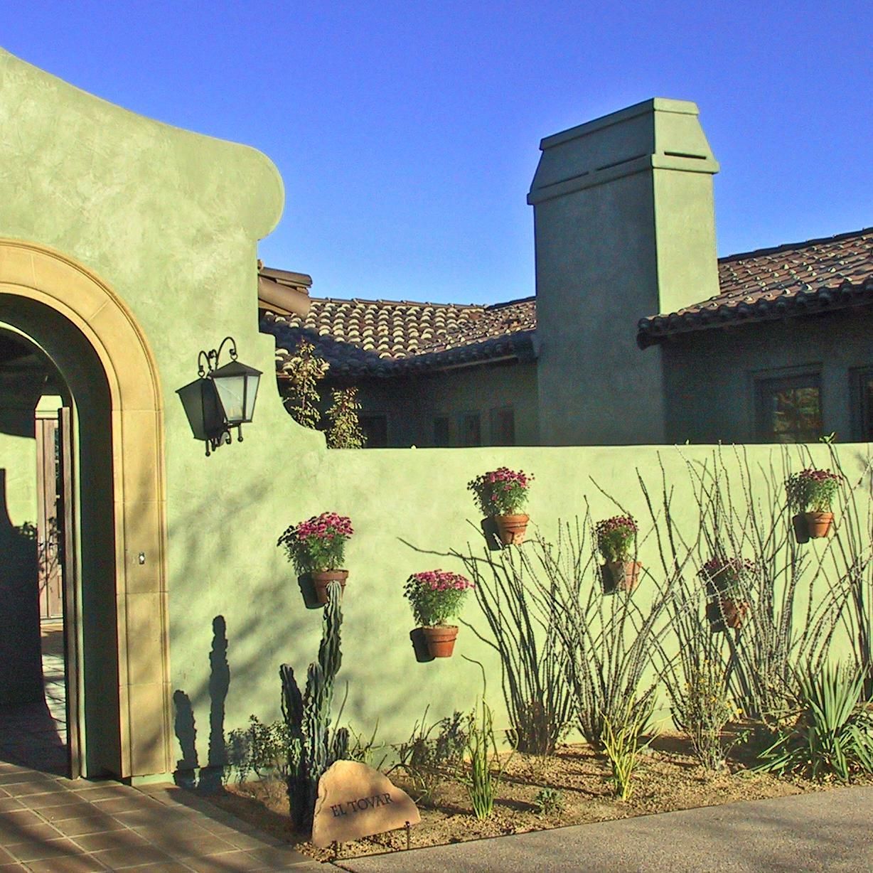 A green wall with potted plants hanging from it