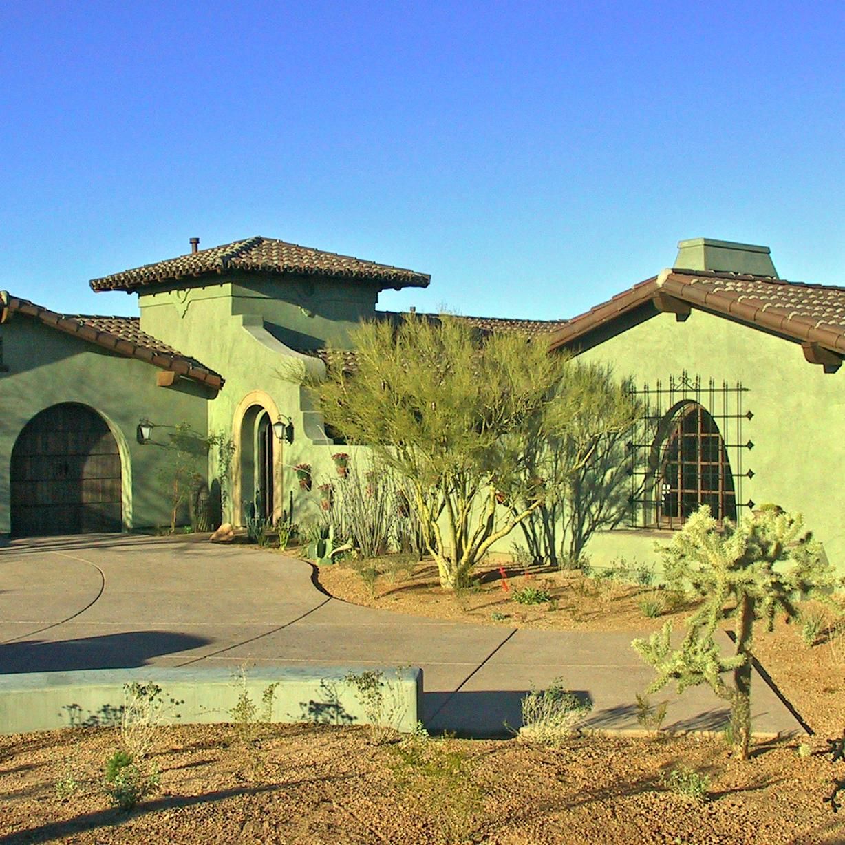 A green house with a brown roof is in the desert