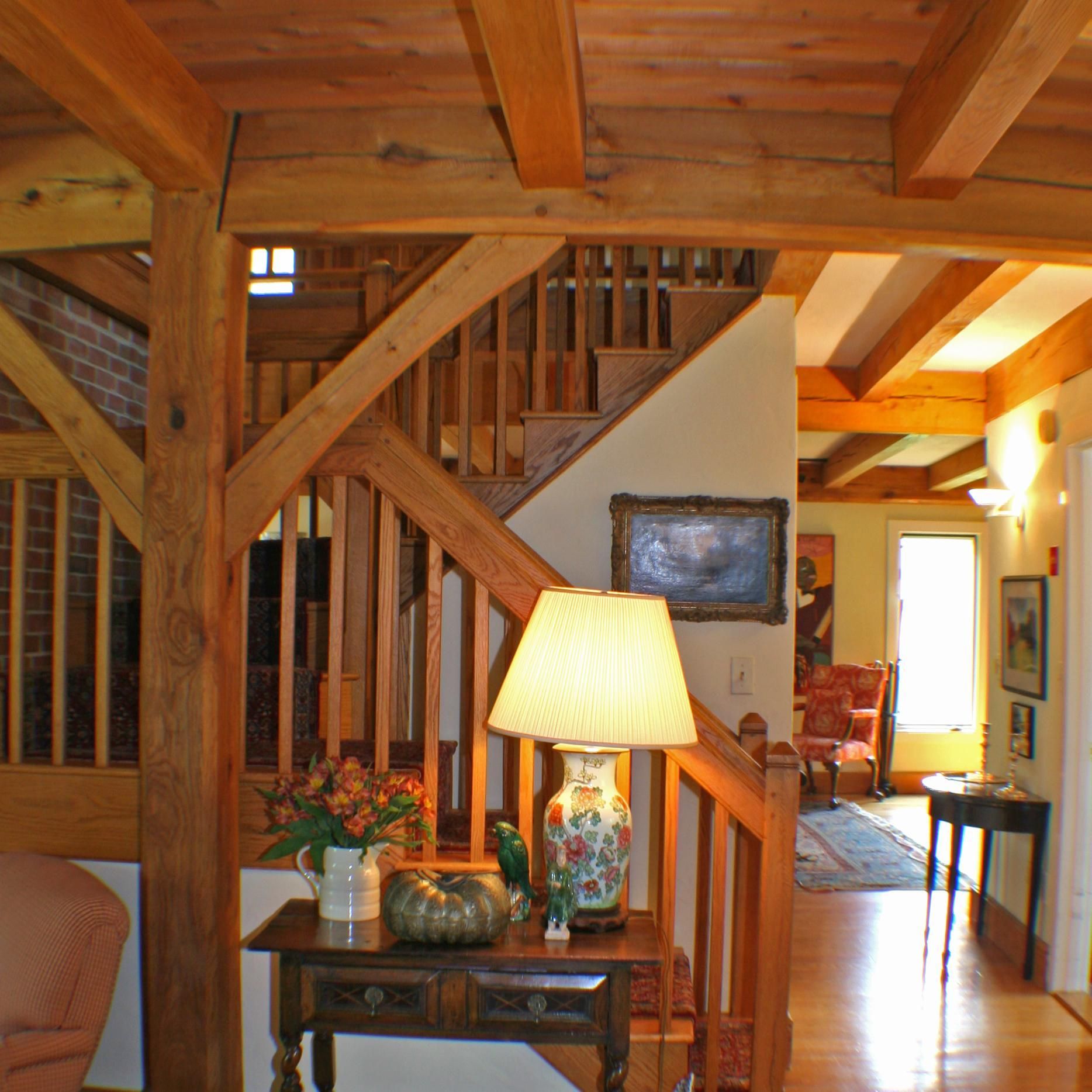 A lamp sits on a table in front of a wooden staircase