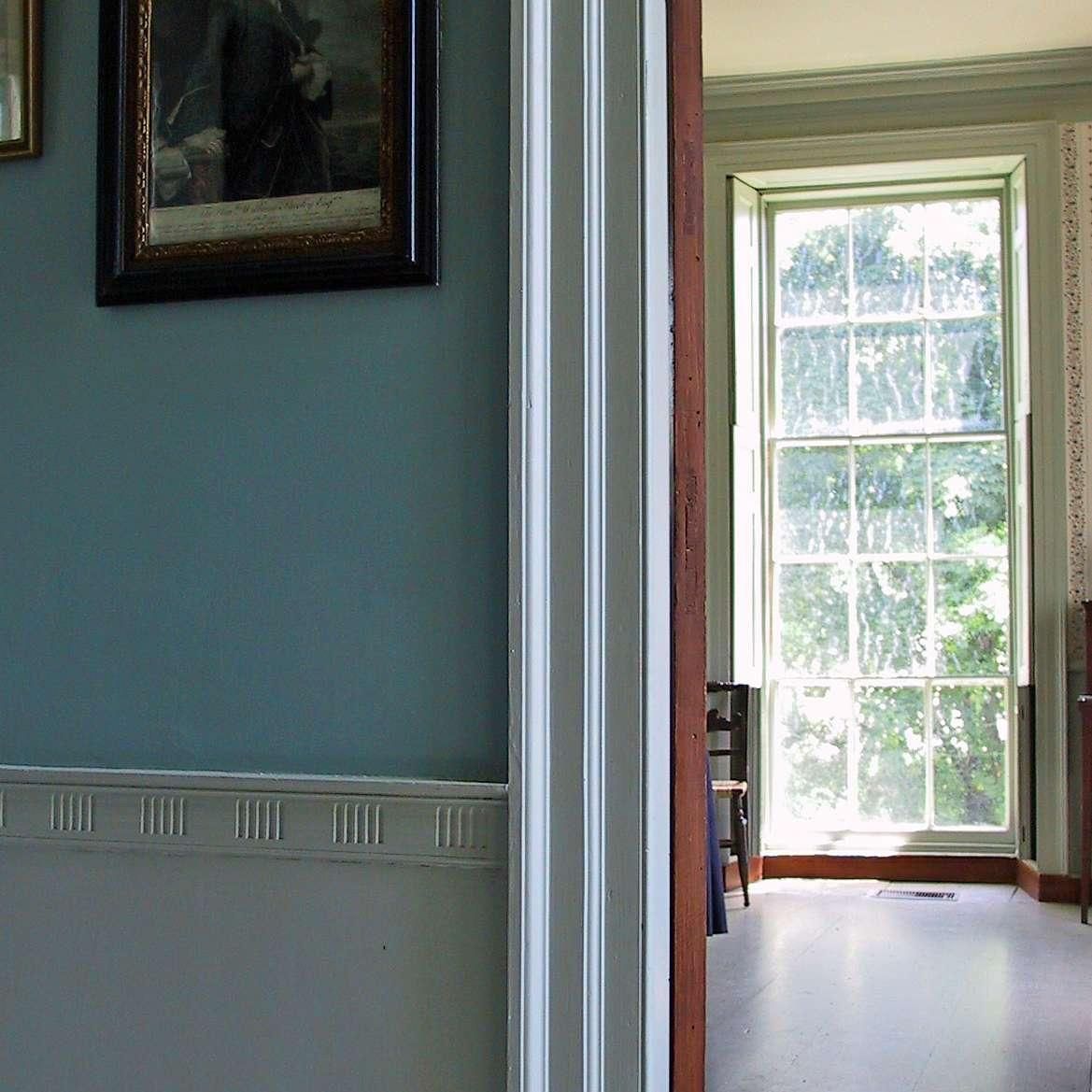 A room with a picture on the wall and a large window