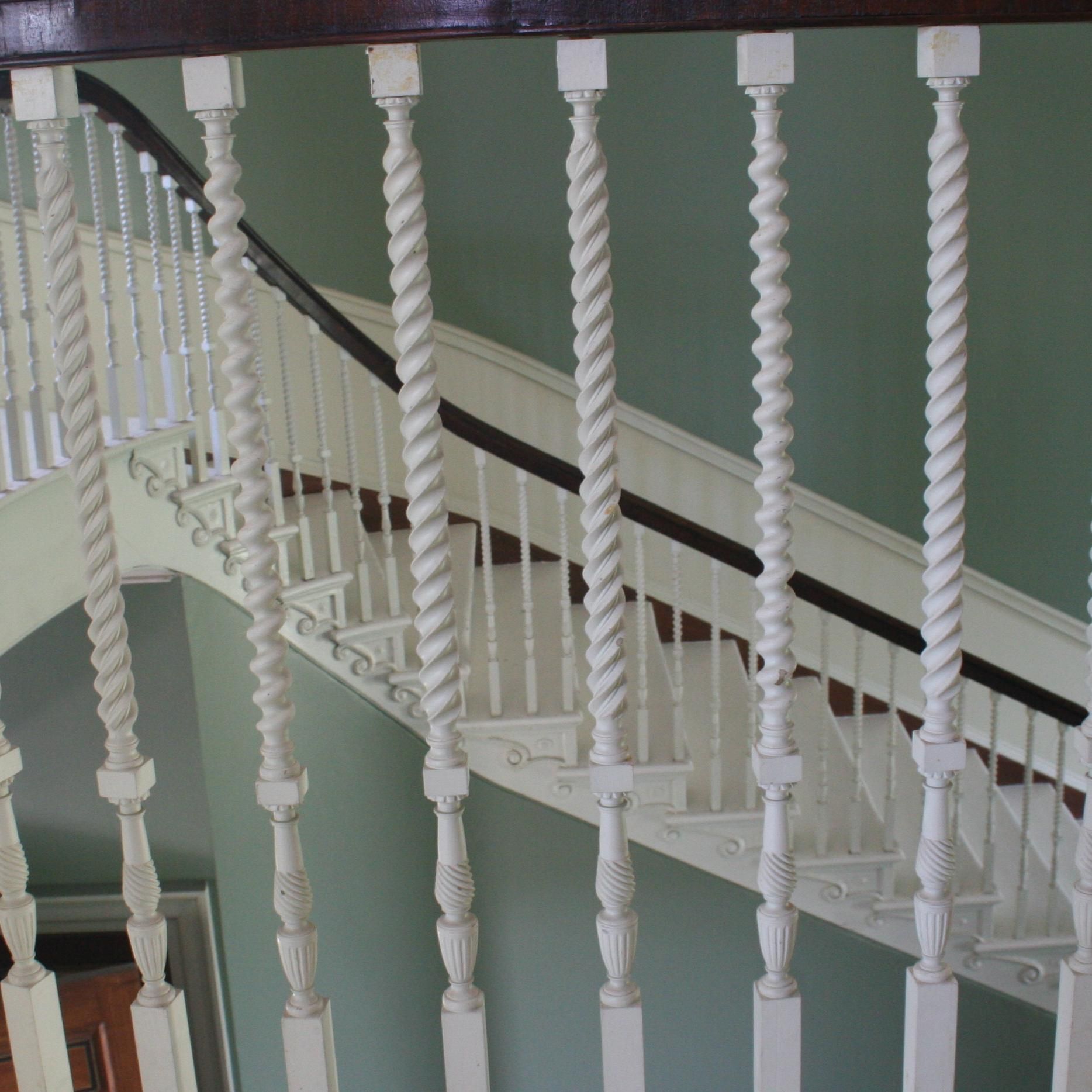 A staircase with white railings and a wooden handrail