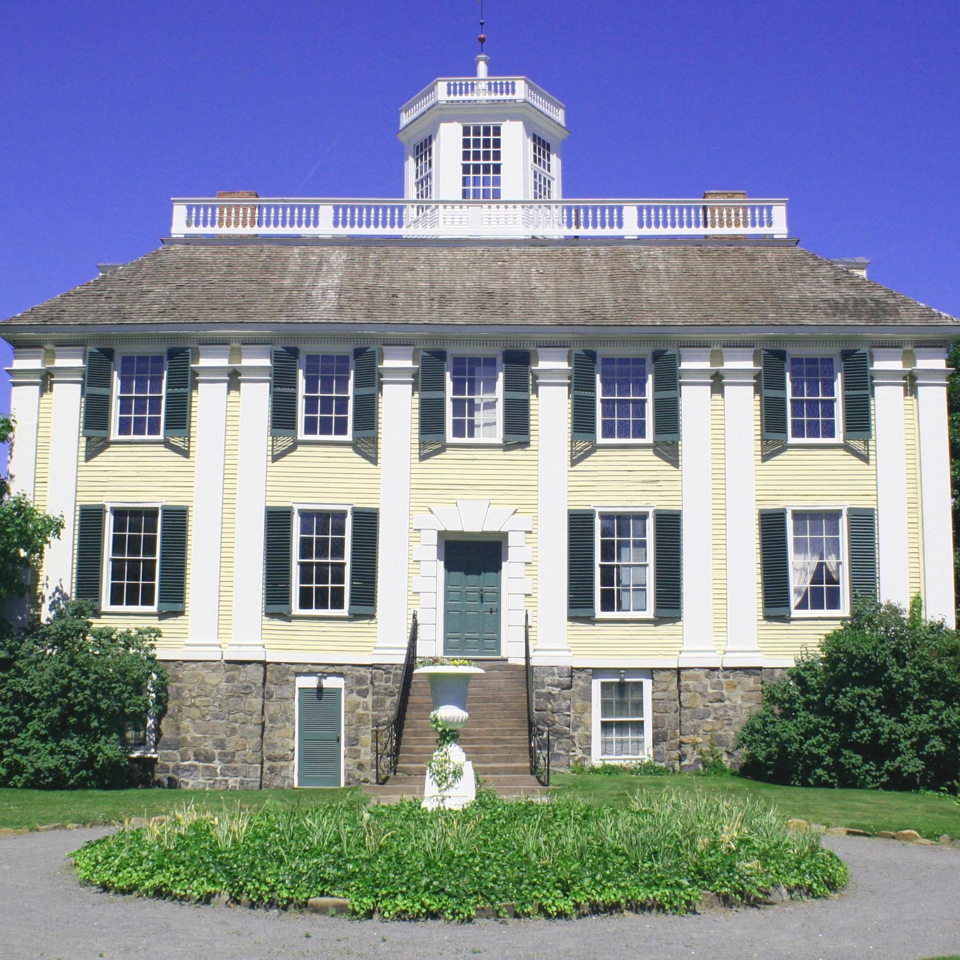 A large yellow and white house with green shutters