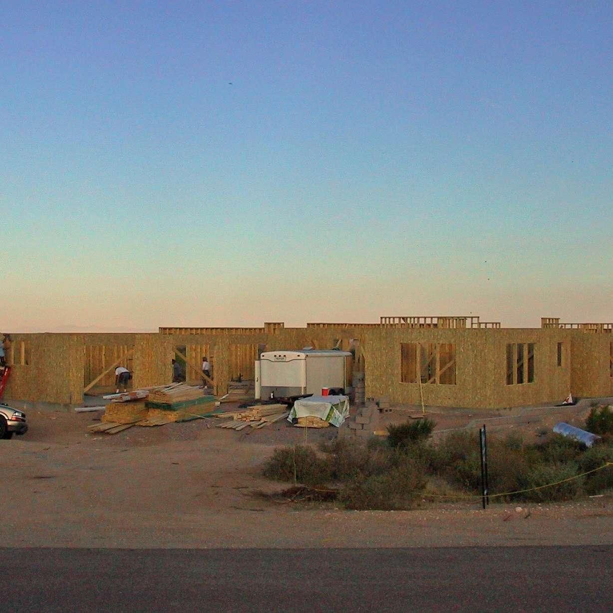 A house is being built in the desert with a blue sky in the background.