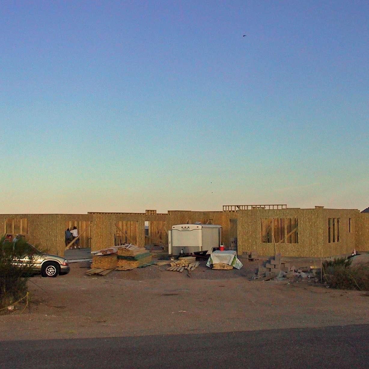 A house is being built in the desert with a blue sky in the background.