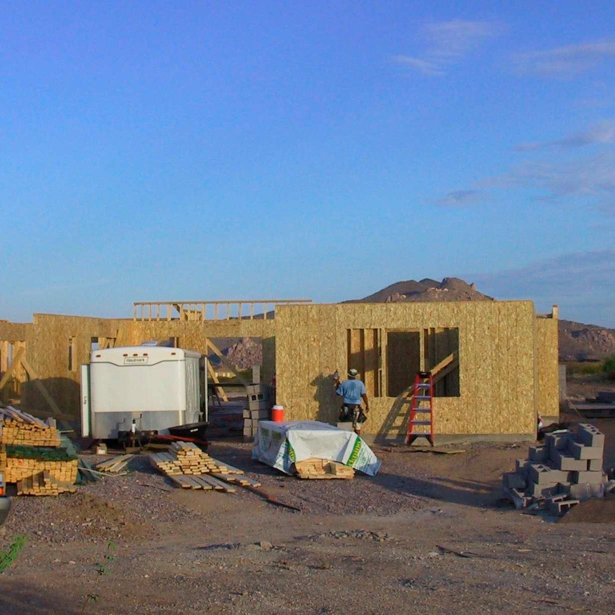 A house is being built in the desert with a ladder in the foreground