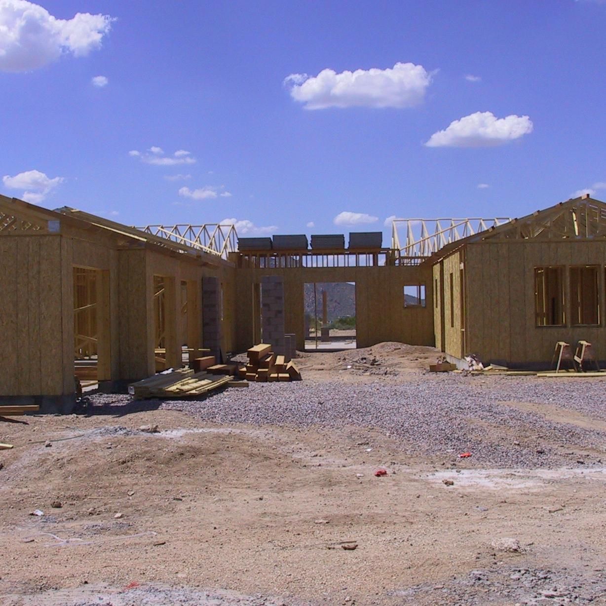 A row of wooden houses under construction with a blue sky in the background