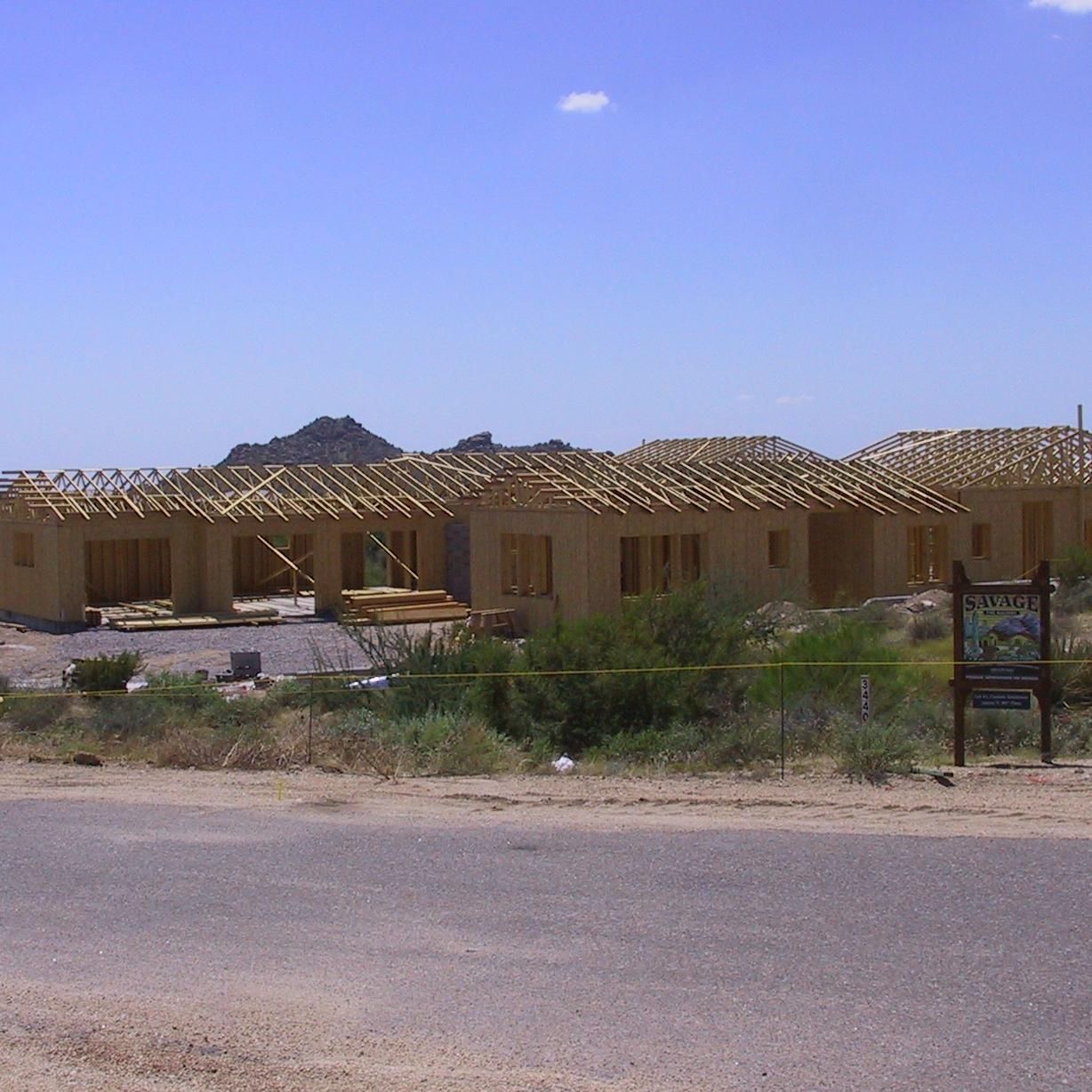 A row of houses under construction with a sign in the foreground