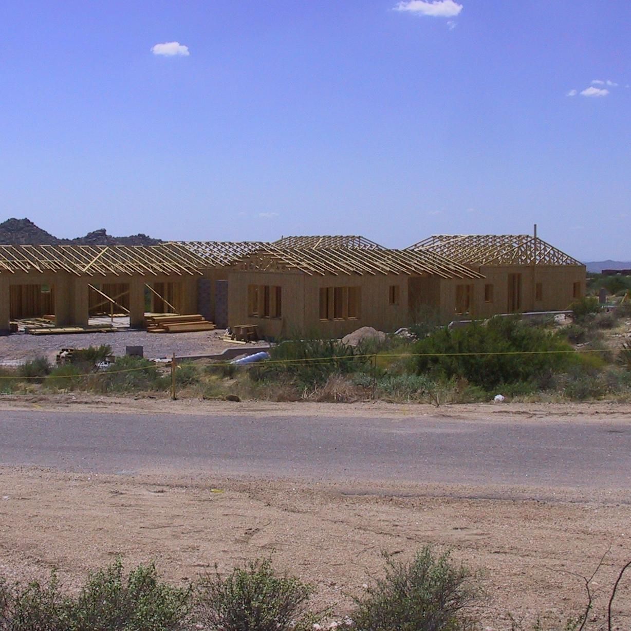 A row of houses under construction with a blue sky in the background